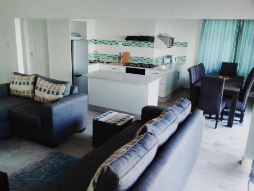 a living room with two couches and a kitchen at Oceans Breeze - Unit 2 Second floor in Durban