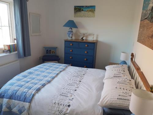 a bedroom with a bed and a blue dresser at Flint Cottage in Gayton
