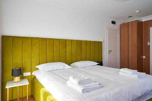 a bedroom with a large white bed with a green headboard at Hotel Glory in Oradea