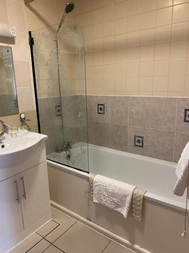 a bathroom with a shower and a tub and a sink at Cardiff Sandringham Hotel in Cardiff