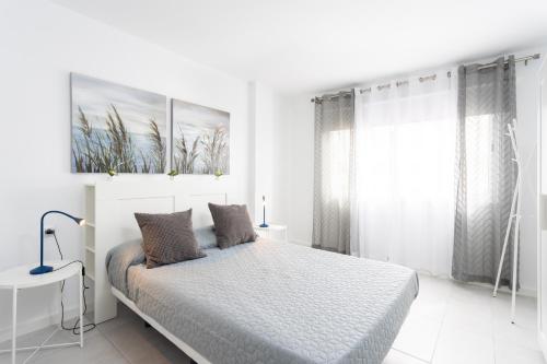 Un dormitorio blanco con una cama y una ventana. en Home2Book Paradise Los Cristianos, Pool & Wifi, en Arona
