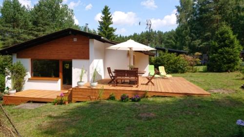 a house with a deck with a table and an umbrella at MAJKÓWKA in Łąkie