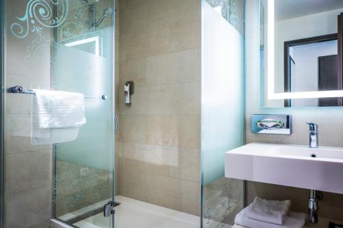 La salle de bains est pourvue d'une douche en verre et d'un lavabo. dans l'établissement VISIONAPARTMENTS Geneva Mont-Blanc, à Genève