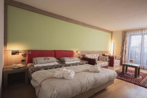 a bedroom with a large bed with towels on it at Hotel Rubino Deluxe in Campitello di Fassa