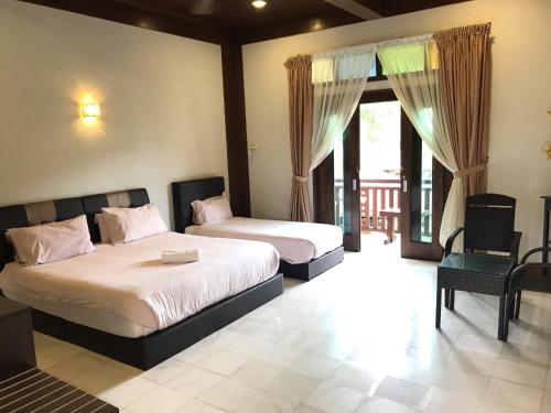 a bedroom with two beds and a balcony at Singgahsana Villa in Pantai Cenang