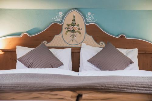 a bed with a wooden head board and pillows at Hotel Rubino Deluxe in Campitello di Fassa