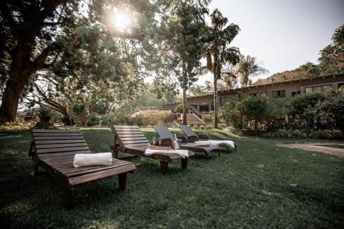 a row of wooden benches sitting in the grass at Linvale Country Lodge in Hazyview