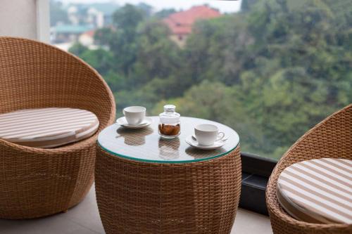 a table with two chairs with cups and a bottle at The Oasis Mussoorie - A Member of Radisson Individuals in Mussoorie