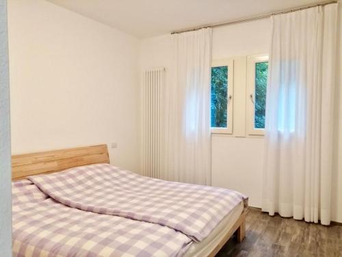 a bedroom with a bed and two windows at Casa Claudio in Nago-Torbole
