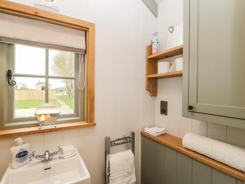 ein Bad mit einem Waschbecken und einem Fenster in der Unterkunft Jasmine Hut, Myrtle Farm in Bristol