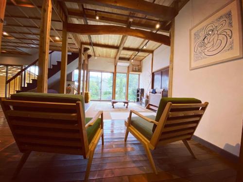 a living room with two chairs and a staircase at yuzaka - natural & sustainable inn - in Kazuno