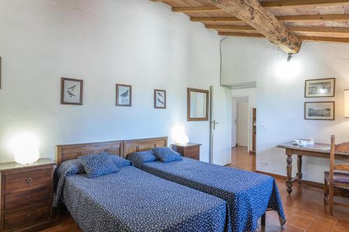 a bedroom with two beds with blue sheets and a table at PODERE SAN ANSANO 14&2, Emma Villas in Paganico