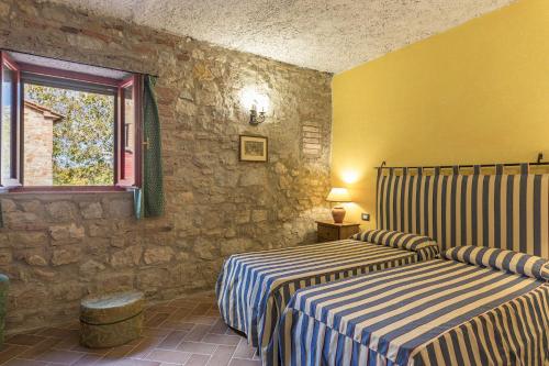 two beds in a room with a stone wall at PODERE SAN ANSANO 14&2, Emma Villas in Paganico