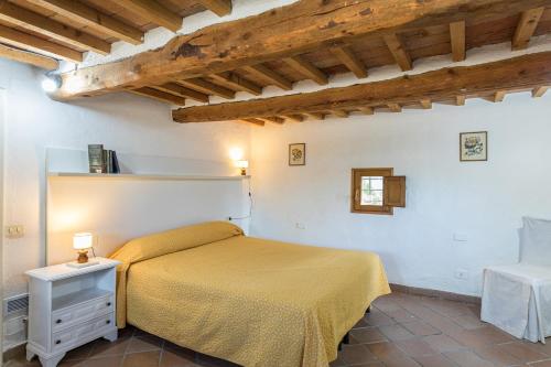 a bedroom with a bed in a room with wooden ceilings at PODERE SAN ANSANO 14&2, Emma Villas in Paganico