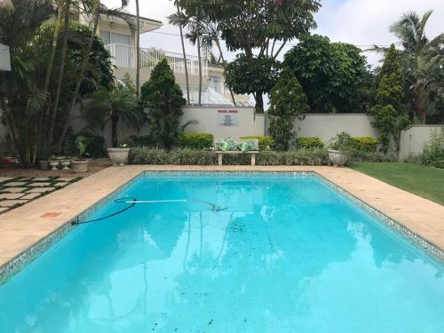 a large blue swimming pool in front of a house at The Studio on Cordia DSTV WIFI 2km from Umhlanga Beach in Durban