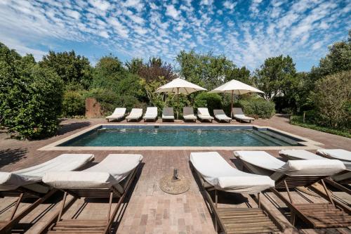 a swimming pool with lounge chairs and umbrellas at Plumwood Inn - Solar Power in Franschhoek