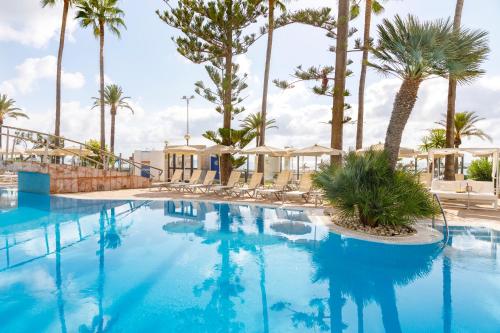 a swimming pool with chairs and palm trees at CM Playa del Moro in Cala Millor