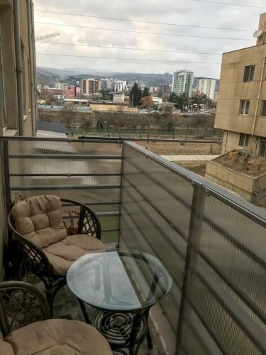 a glass table and chairs on a balcony with a view at Cozy Apartment In Ortacahala in Tbilisi City