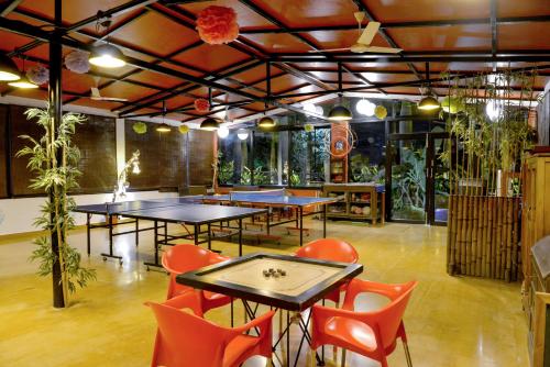a restaurant with ping pong tables and orange chairs at Anchaviyo Resort in Vāda