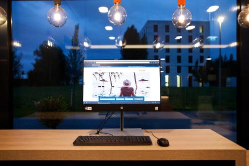 a computer monitor and a keyboard and mouse on a desk at Holiday Inn Express - Lustenau in Lustenau