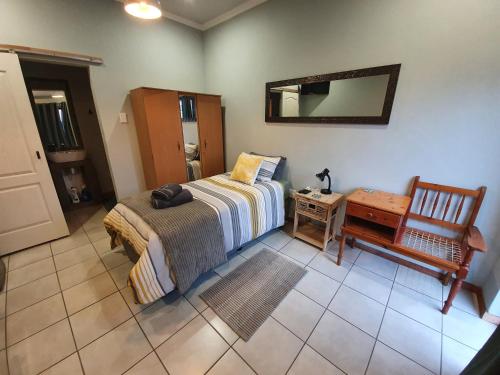 a bedroom with a bed and a chair and a mirror at Delikaat Bed & Coffee in Prieska