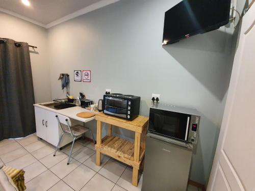a small kitchen with a microwave and a table with a microwave at Delikaat Bed & Coffee in Prieska