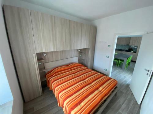 ein Schlafzimmer mit einem Bett mit einer orangefarbenen gestreiften Decke in der Unterkunft Appartamenti Nadalini in Levico Terme