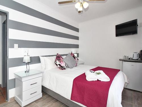 - une chambre avec un lit et une couverture rouge dans l'établissement Glennies Guesthouse, à Somerset West