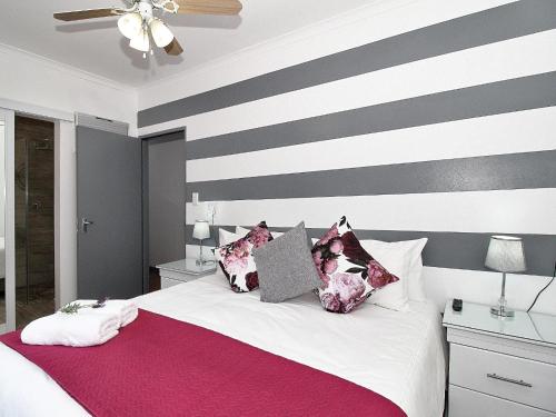 sypialnia z łóżkiem ze ścianą z paskami w obiekcie Glennies Guesthouse w mieście Somerset West