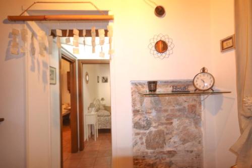 a hallway with a stone wall and a clock on a wall at Piccola casetta toscana in Pisa