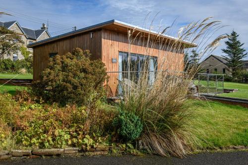 a small wooden house in a yard with plants at Dunnet B&B Escapes in Dunnet