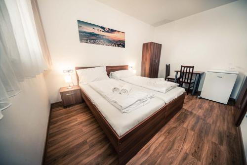 a bedroom with a bed with white sheets and wooden floors at Penzion Třetí frejd in Bořetice