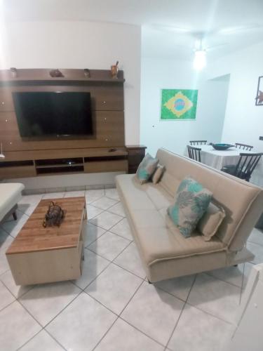 uma sala de estar com um sofá e uma televisão de ecrã plano em Cantinho do Boris l em Ubatuba