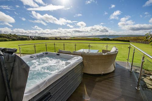 a hot tub on a deck with a view of a field at Dunnet B&B Escapes in Dunnet