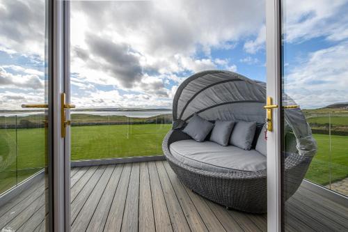 a wicker chair sitting on a deck next to a window at Dunnet B&B Escapes in Dunnet