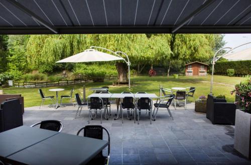 a patio with tables and chairs and an umbrella at Sure Hotel by Best Western Lille Tourcoing Ex Hotel Garden in Bondues