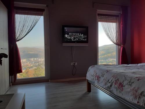 a bedroom with a bed and two large windows at Banat Residence in Reşiţa