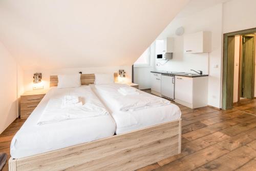 een slaapkamer met een groot wit bed en een keuken bij Mentenwirt Suite in Sankt Martin