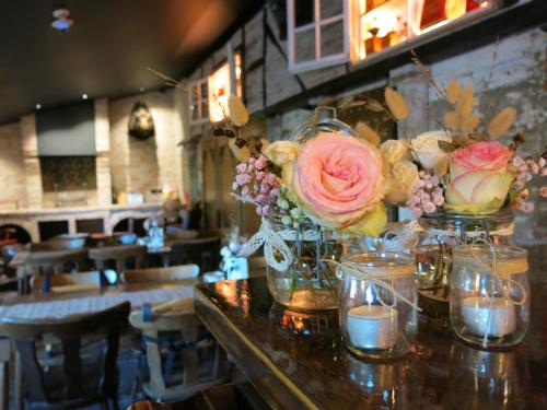 a table with vases of flowers and candles on it at Hoeve Chartreuse in Bruges