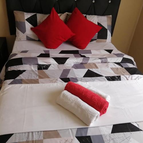 a bed with red and white pillows on it at ROYAL LODGE in Witbank