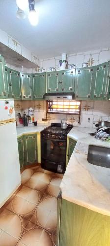 a kitchen with green cabinets and a stove top oven at Casona LA FLORIDA con parque y pileta, a una cuadra del río in Rosario