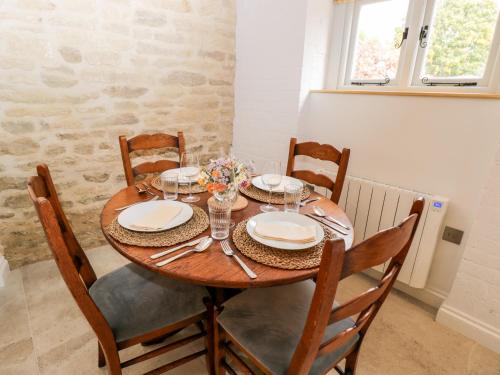 a wooden table with chairs and plates on it at The Old Swill House in Chippenham