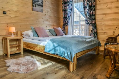 - une chambre avec un lit dans une pièce en bois dans l'établissement Domki 4 Seasons Zakopane, à Zakopane