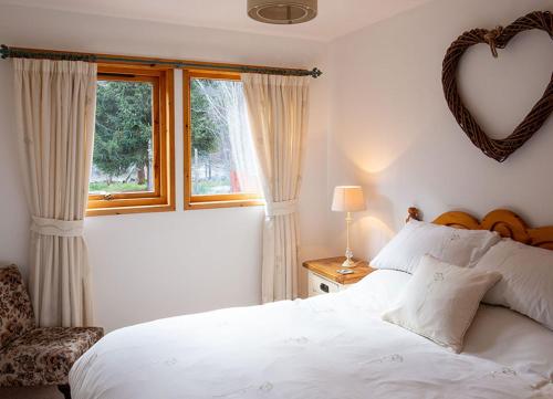 1 dormitorio con cama blanca y ventana en Croftwood Cottage, en Boat of Garten