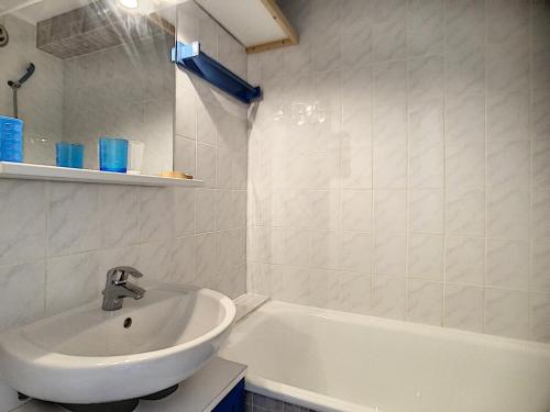 a white bathroom with a sink and a bath tub at travelski home classic - Résidence Caron in Les Menuires