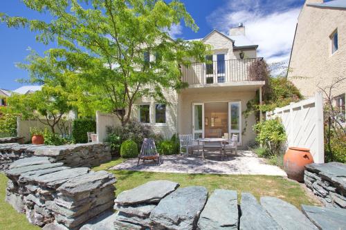 a yard with a stone wall and a house at Millbrook Resort in Arrowtown