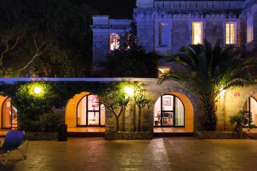 a building with arches and palm trees at night at SC Club Village in Pembroke 