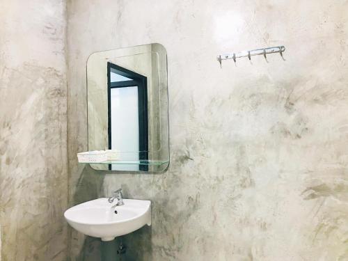 La salle de bains est pourvue d'un lavabo et d'un miroir mural. dans l'établissement ใสโพธิ์โฮมสเตย์, à Phatthalung
