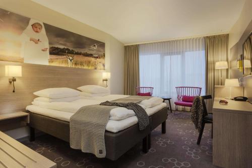 ナルヴィクにあるスカンディック ナルビクの大きなベッドとデスクが備わるホテルルームです。