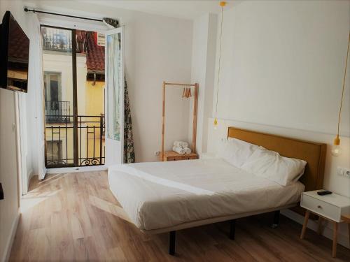 1 dormitorio con cama y ventana grande en Hostal Manuela by gaiarooms, en Madrid